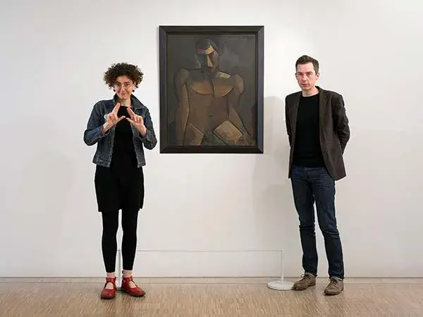 Photo de deux personnes expliquant une œuvre avec le langage des signes